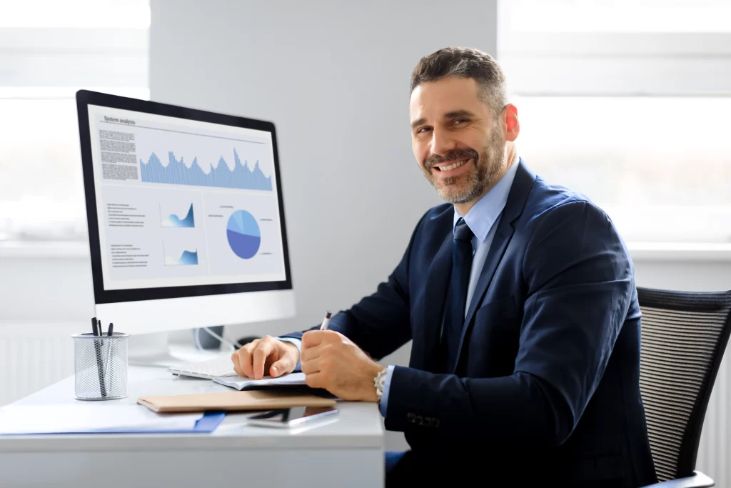 a imagem mostra um empresário sorrindo e no seu computador os resultados do marketing de sua indústria e ilustra o artigo que fala sobre uma agência de marketing em Divinópolis especializada no setor de indústrias